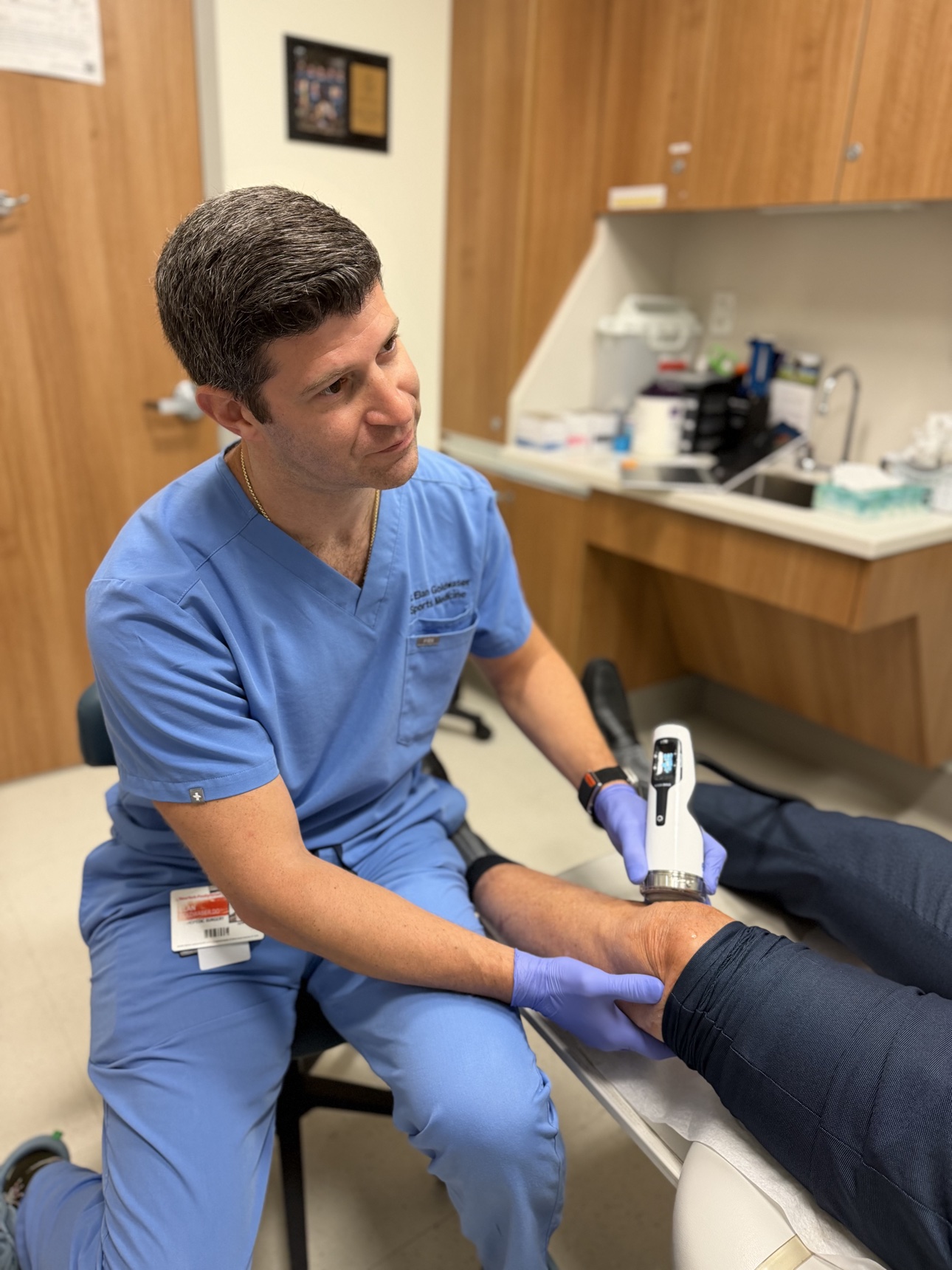 Dr. Goldwaser administering shockwave therapy to a patient’s knee