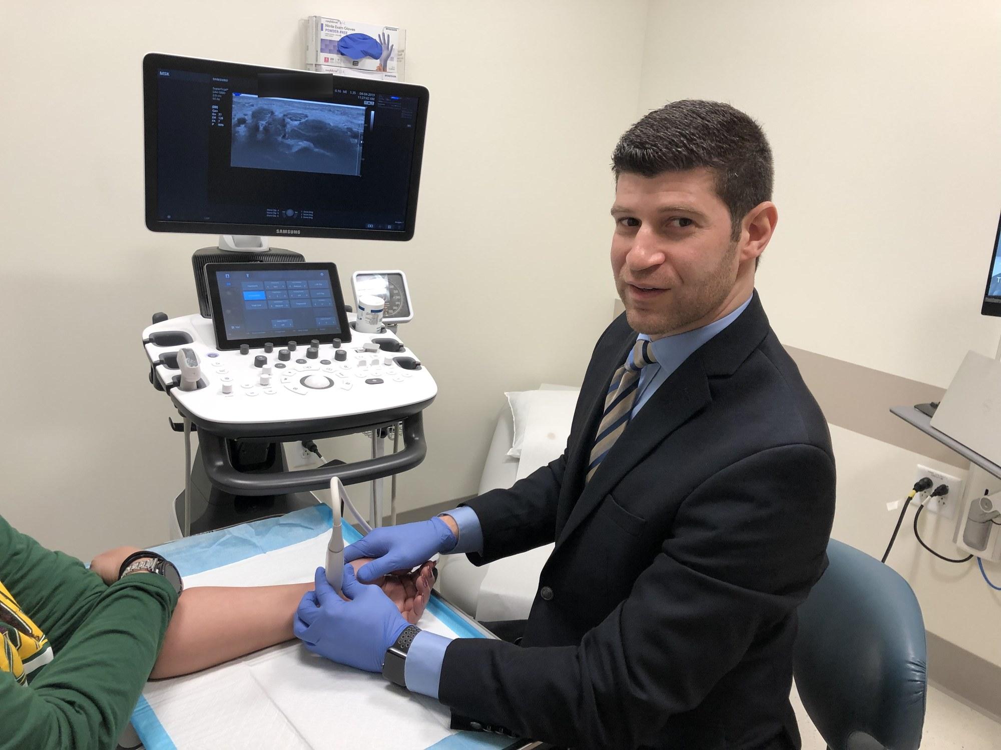 Dr. Goldwaser using ultrasound to examine a patient’s forearm